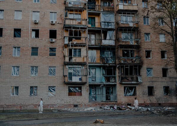 Two women stand in front of a residential building in southern Russia that was damaged by a missile.